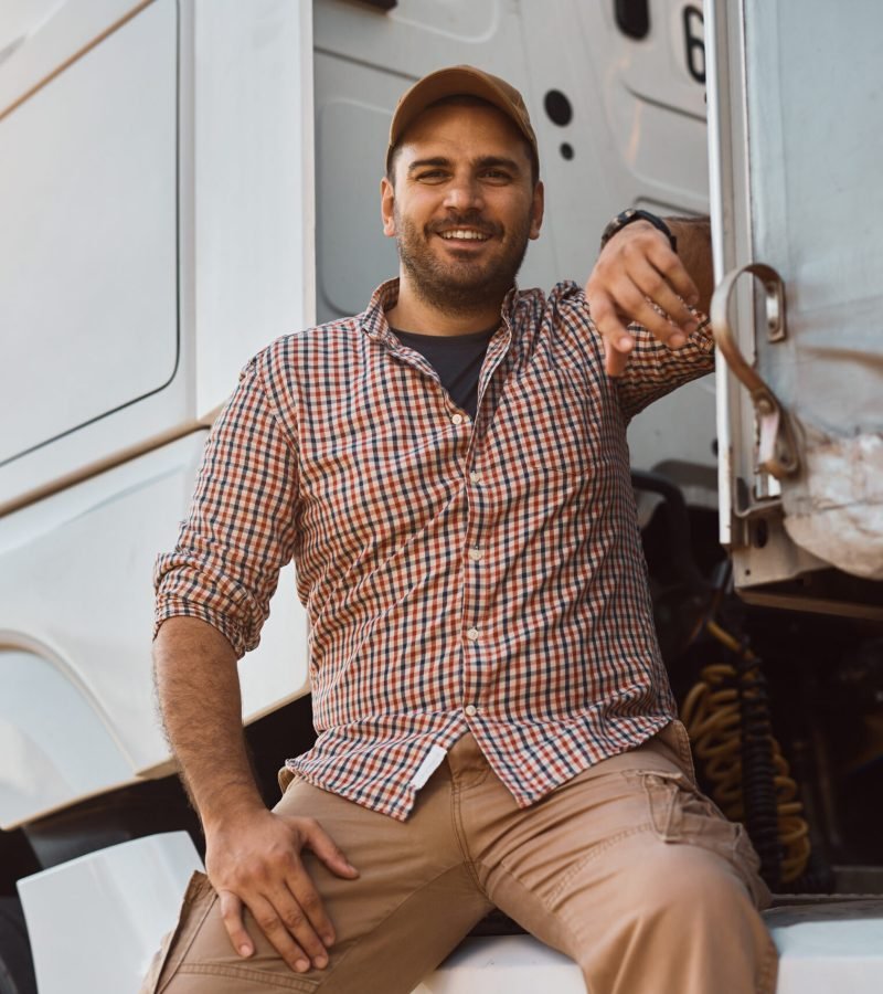 Happy professional truck driver outdoors looking at camera.